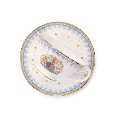 White fine bone china teacup and matching saucer, featuring a blue scalloped border with gold-plated trim, gold polka dot accents, and a decorative royal-style crest on the cup. 