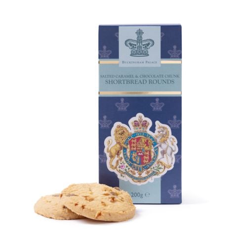 Front view of a Buckingham Palace Salted Caramel & Chocolate Chunk Shortbread Rounds box in navy blue and light blue, featuring the Royal Coat of Arms with a lion and unicorn, displayed with two shortbread biscuits containing caramel and chocolate pieces 