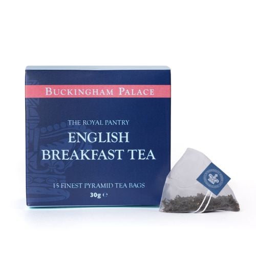 Box of English Breakfast Tea from The Royal Pantry, Buckingham Palace range, presented in a navy blue carton with pink detailing and a subtle crown-inspired pattern. The box contains 15 finest pyramid tea bags, with a single pyramid tea bag filled with lo