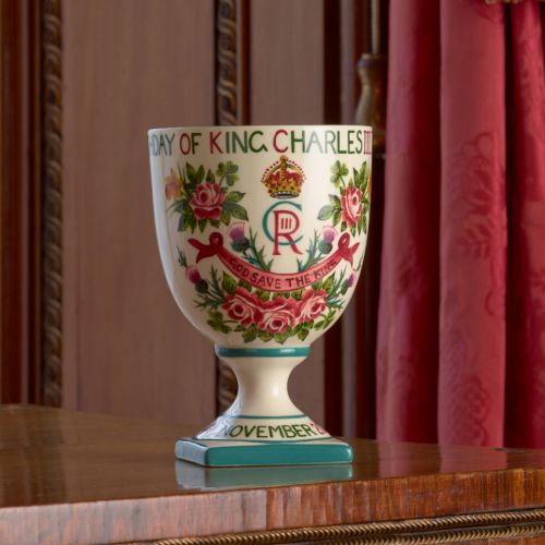 Back of goblet. Goblet is on a table with ornate background of wood and curtains in one of Buckingham Palace state rooms.