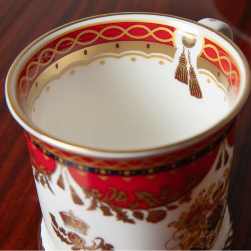 The Livery Takard, featuring the royal coat of arms 
 with a deep, rich scarlett design and navy border with contrasting fine gold details, inspired by the intricate decorative braiding of hand-sewn livery and regimental devices of ceremonial uniforms. 