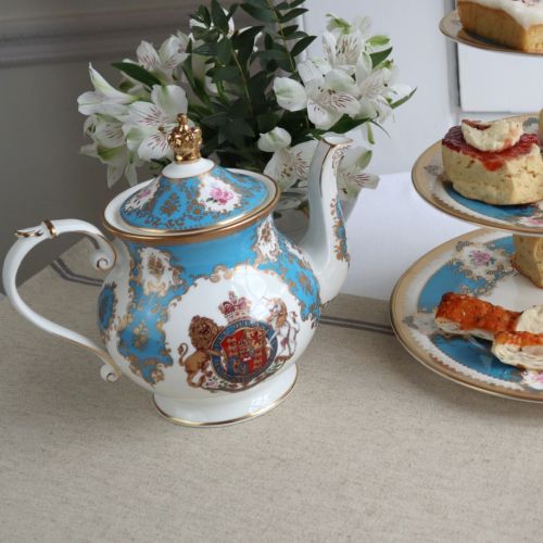 Royal coat of arms English fine bone china 6 cup Teapot featuring a lion and unicorn royal crest surrounded by ornated gold patterns and English flower patterns on a turquoise blue coloured background. The lid is topped with with a royal gold crown. 