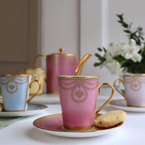 The full Imperial Russian cup and saucer set displayed in a gift box with a design featuring gilded borders and ornated gold patterns in 6 individual pastel coloured backgrounds. Green, yellow, turquoise, pink, blue and purple. 