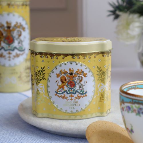 Tin tea caddy is yellow and decorated with the Royal Coat of Arms, leaves tied with bows and acorns.  