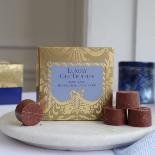 A golden chocolate box with blue writing and centre, stating "Luxury Gin Truffles, made using Buckingham Palace Gin."