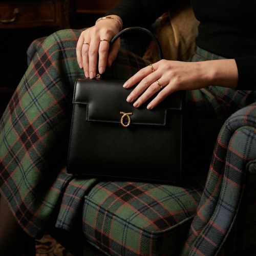 Royal Collection Trust x Launer Traviata black bag featuring straps, and mirror with collboration branding as well as gold clasps. 
