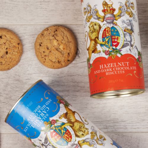 Orange cardboard tube of Hazelnut and dark chocolate biscuits. The lion and unicorn crest is at the centre of the design underneath the words 'Windsor Castle.' Next to the tube are two biscuits.