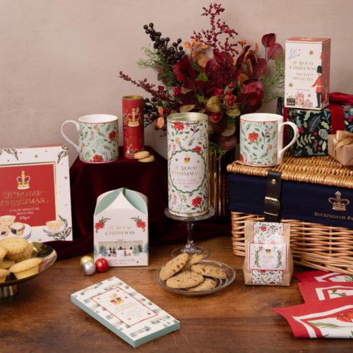 Wicker hamper with two festive mugs, two tubes of biscuits, mince pies, tea, chocolate bar, chocolate lumps of coal, a box of truffles and 2 festive napkins.