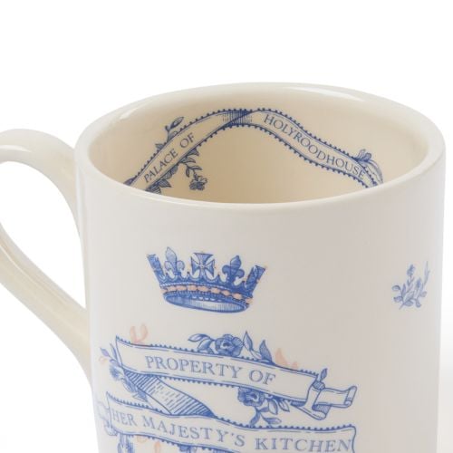 Cream earthenware mug with blue typeface and copper detailing that states property of Her Majesty's kitchen.