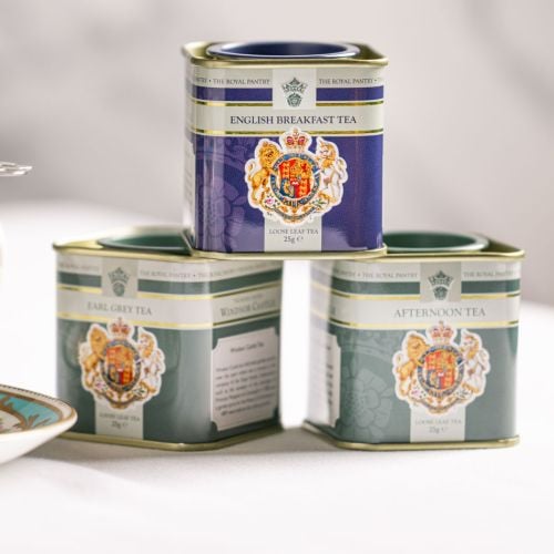 Three loose leaf tea caddies from The Royal Pantry arranged on a light surface, featuring English Breakfast Tea, Earl Grey Tea and Afternoon Tea. The decorative tins display the Royal Coat of Arms and are stacked with the English Breakfast Tea caddy balan