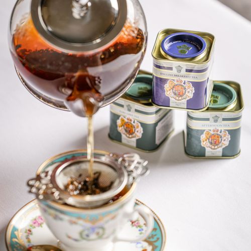 Three loose leaf tea caddies from The Royal Pantry arranged on a light surface, featuring English Breakfast Tea, Earl Grey Tea and Afternoon Tea. The decorative tins display the Royal Coat of Arms and are stacked with the English Breakfast Tea caddy balan