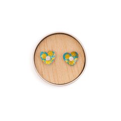 Blue heart earrings with a gold design in a small round tin.