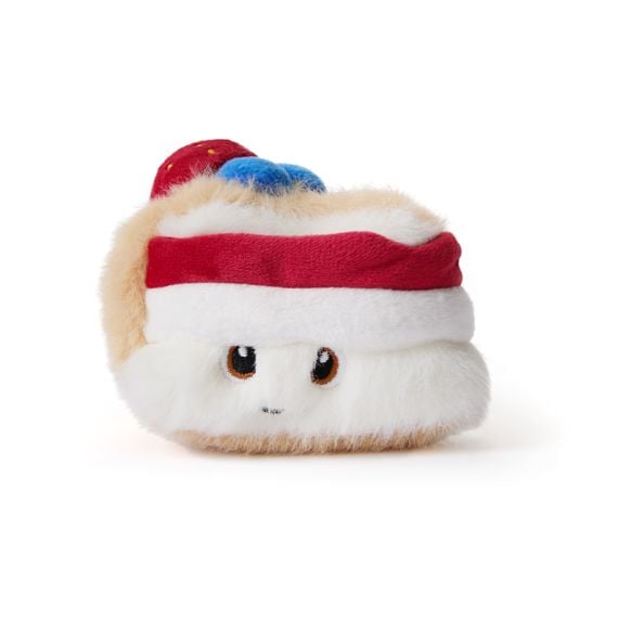 Cake plushie toy with eyes and smiley face, with a red band and fruit on top. 