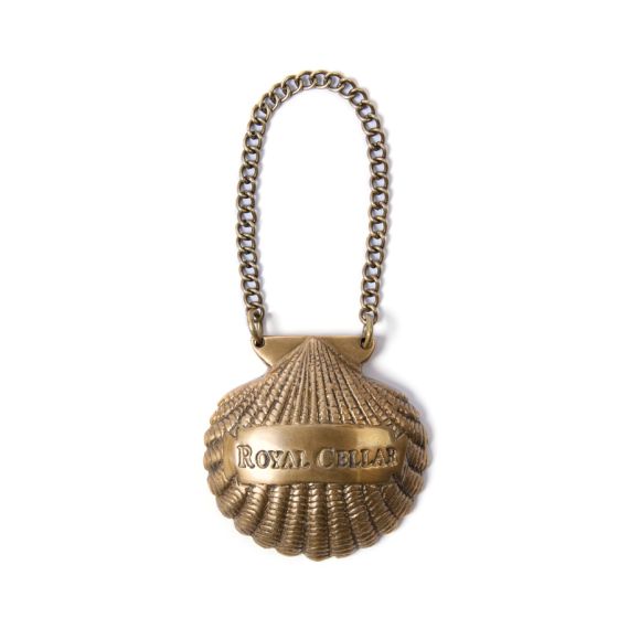 Brass bottle charm in shape of a shell, labelled Royal Cellar. Brass bottle charm in shape of a shell, labelled Royal Cellar.