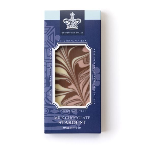 Front of “Milk Chocolate Stardust” chocolate bar from The Royal Pantry, Buckingham Palace. The deep blue packaging features a white crown emblem and decorative motif, with a window revealing marbled milk, white, and pink strawberry chocolate swirls.