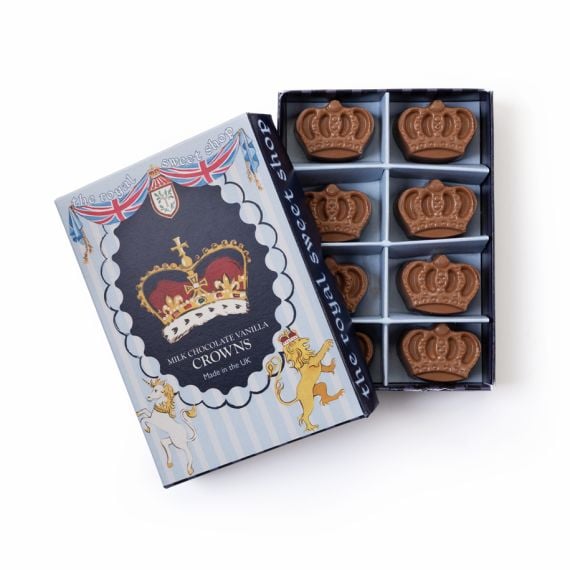 Open box of milk chocolate vanilla crowns from The Royal Sweet Shop, showing nine crown-shaped chocolates arranged in a tray beside the illustrated lid.
