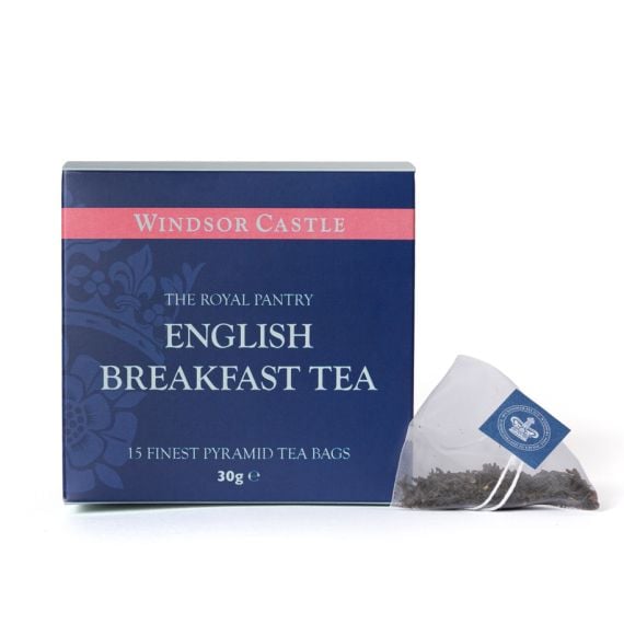Box of English Breakfast Tea from The Royal Pantry, Windsor Castle range, presented in a navy blue carton with pink detailing and a floral pattern. The box contains 15 finest pyramid tea bags, with a single pyramid tea bag filled with loose tea leaves dis