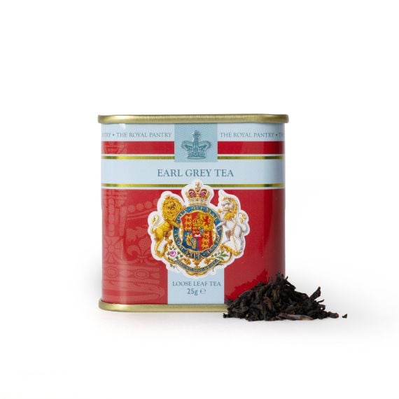 Tin of Earl Grey Tea from The Royal Pantry, featuring a red and pale blue design with the Royal Coat of Arms and crown motif. The gold-lidded tin contains 25g of loose leaf tea, with a small pile of dark tea leaves displayed beside it.
