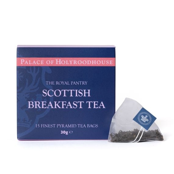 Box of Scottish Breakfast Tea from The Royal Pantry, Palace of Holyroodhouse range, presented in a navy blue carton with pink detailing. The box contains 15 finest pyramid tea bags, with a single pyramid tea bag filled with loose tea leaves displayed besi