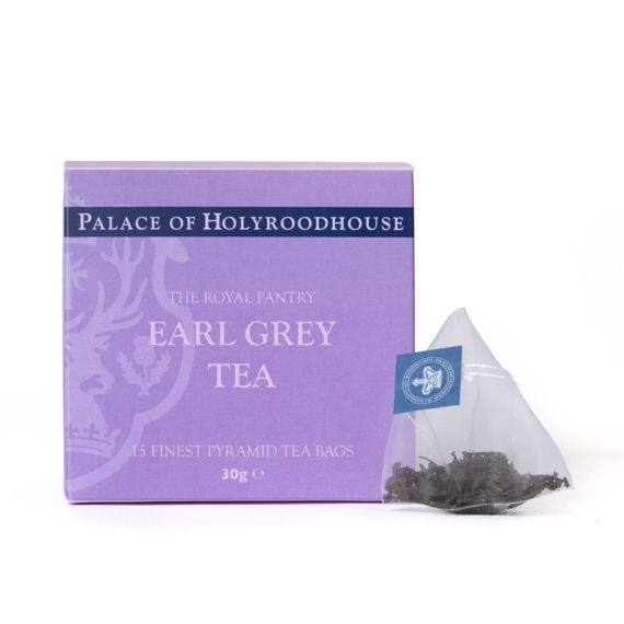 Box of Earl Grey Tea from The Royal Pantry, Palace of Holyroodhouse range, presented in a soft purple carton with navy detailing. The box contains 15 finest pyramid tea bags, with a single pyramid tea bag filled with loose tea leaves displayed beside it.