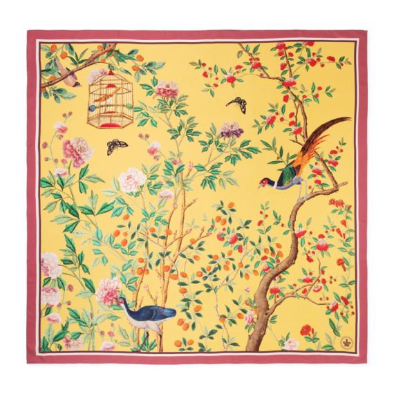 Yellow floral scarf featuring illustrated birds, flowering branches, berries and a hanging birdcage, finished with a pink border.