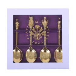 Square lilac box with clear lid. The box contains gold spoons each featuring a symbol at the top of the spoon, these include the orb, the sceptre, crown and throne