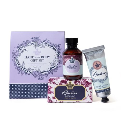 Amber bath and body set with hand cream, bath foam and soap bar in coordinated floral and crown‑detail packaging, made in the UK.