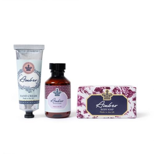 Amber bath and body set with hand cream, bath foam and soap bar in coordinated floral and crown‑detail packaging, made in the UK.