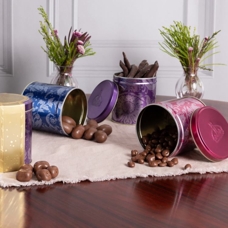 Three sweet tins in blue, purple and pink, displayed on a table