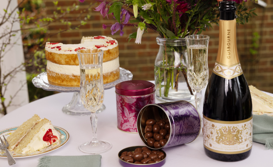 A selection of sweet tins on a dinner table with champagne and a cake